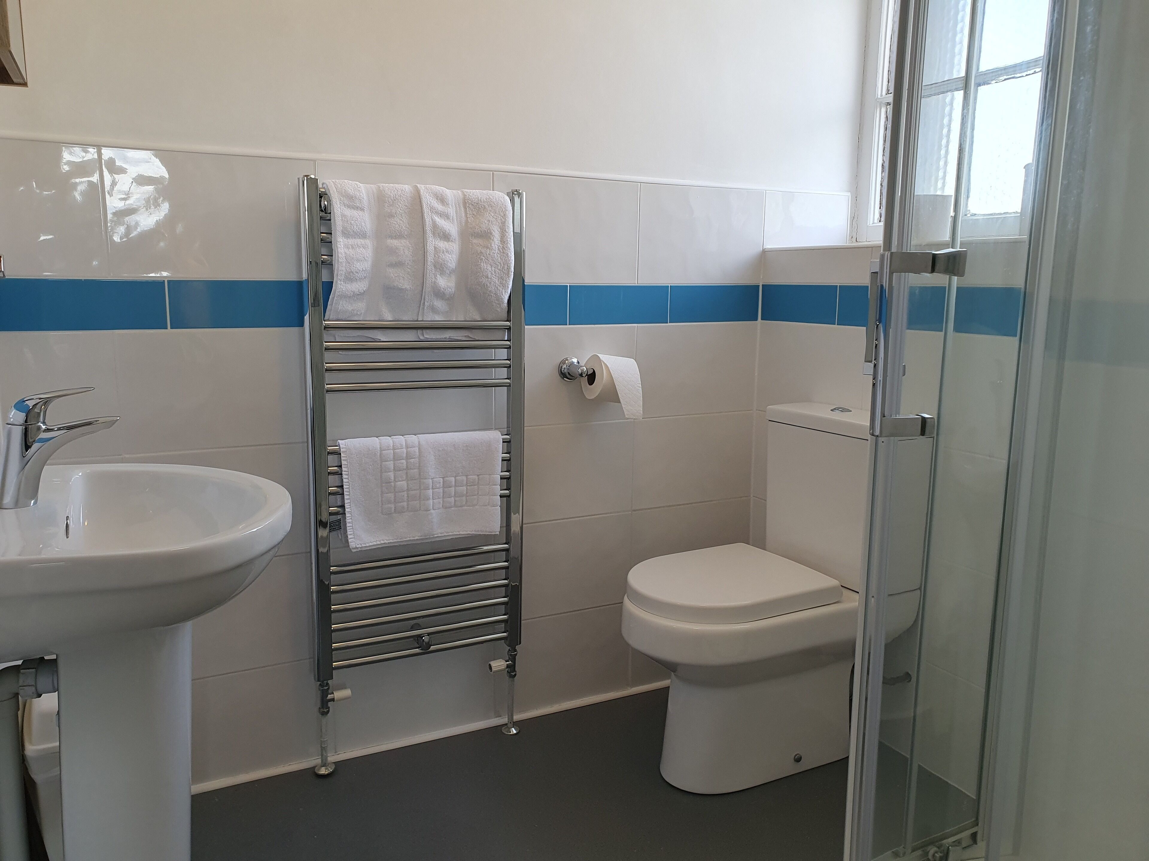 Un baño con lavabo, toallero, inodoro y cabina de ducha de vidrio.