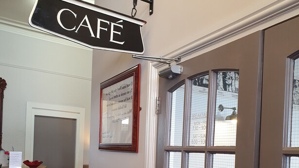A cafe sign, a framed notice, a pull door, and a red bowl on a counter. - The Royal Hotel (Jedburgh)