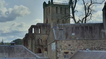 Un edificio histórico de piedra con una torre, que presenta ventanas arqueadas y un letrero que anuncia fish & chips y pizzas.