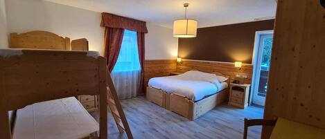 Una habitación con una cama, un escritorio y una silla. Hay una ventana con cortinas y una lámpara en la pared.