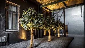 Un intérieur moderne avec un mur en briques noires, une fenêtre avec des stores et un plafond avec des poutres apparentes.