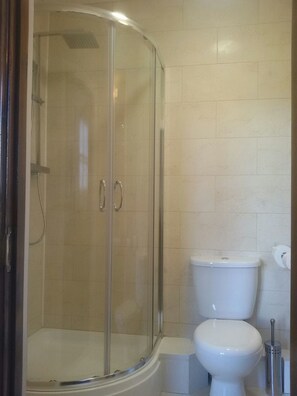 A bathroom with a glass-enclosed shower, a toilet, and a bidet.