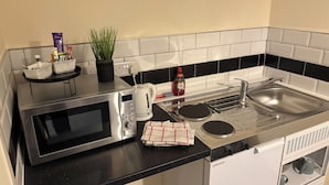 A compact kitchen with a microwave, kettle, sink, and a small dishwasher. - The Sleepwell Inn (Workington)