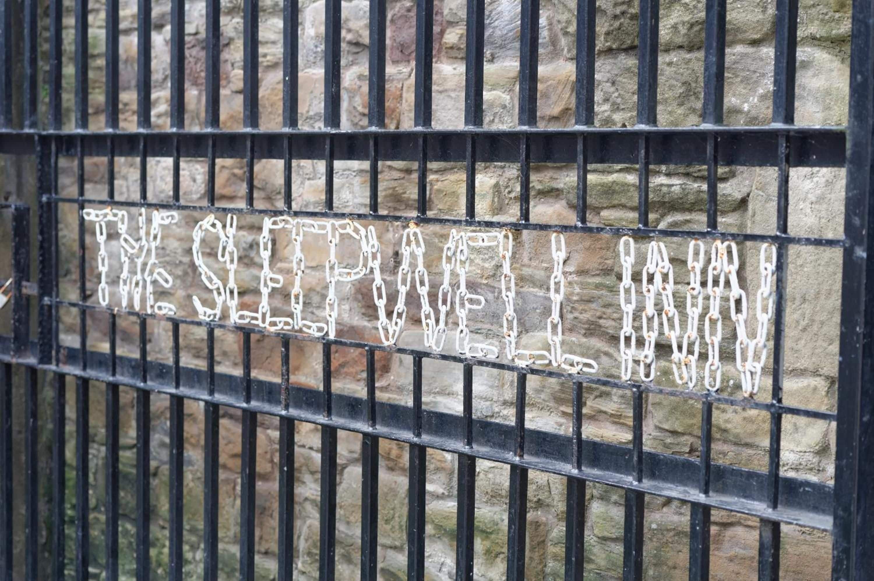 Une porte en métal sur laquelle on peut lire, en lettres blanches, l’inscription « THE SEPAWELL INN ».