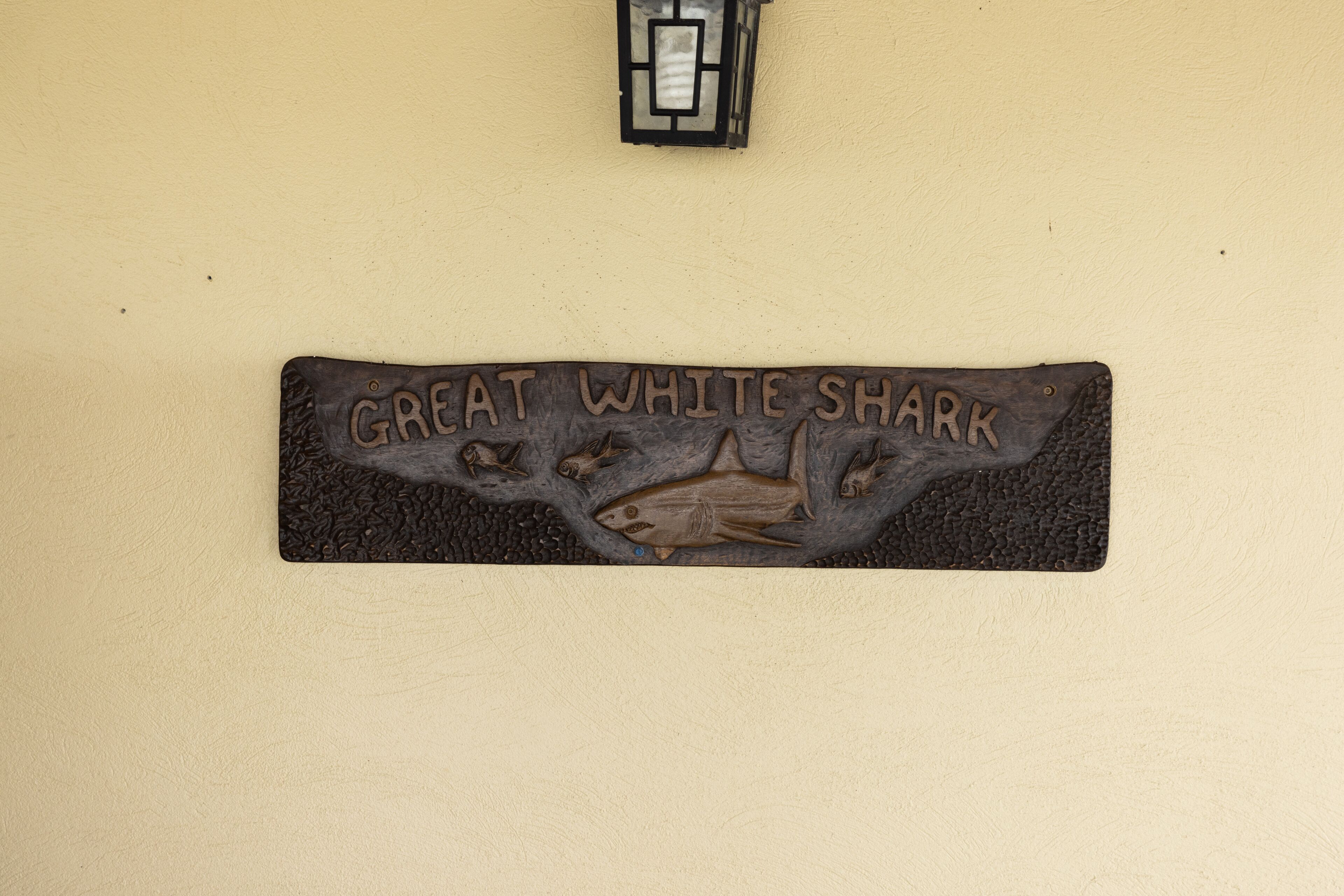 Een houten bord met een haai-ontwerp en de tekst 'GREAT WHITE SHARK'.