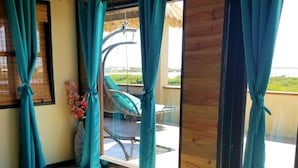 A room with a bed, teal curtains, a window with a view, and a wooden ceiling. - Lina Point Belize Overwater Resort (San Pedro)