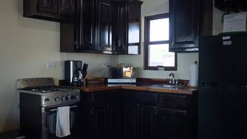 Una cocina con gabinetes de madera oscura, un horno de acero inoxidable, un microondas y un refrigerador.