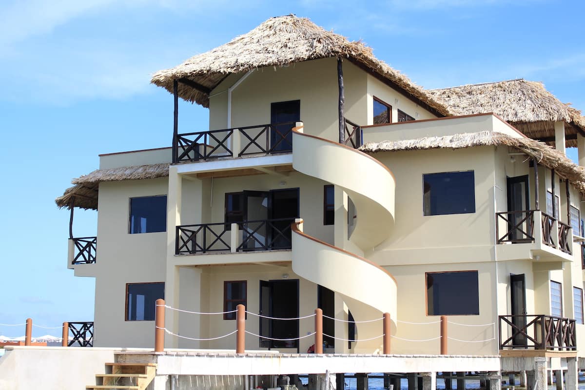 A multi-story hotel with a spiral staircase, balconies with thatched roofs, and a view of the sea.