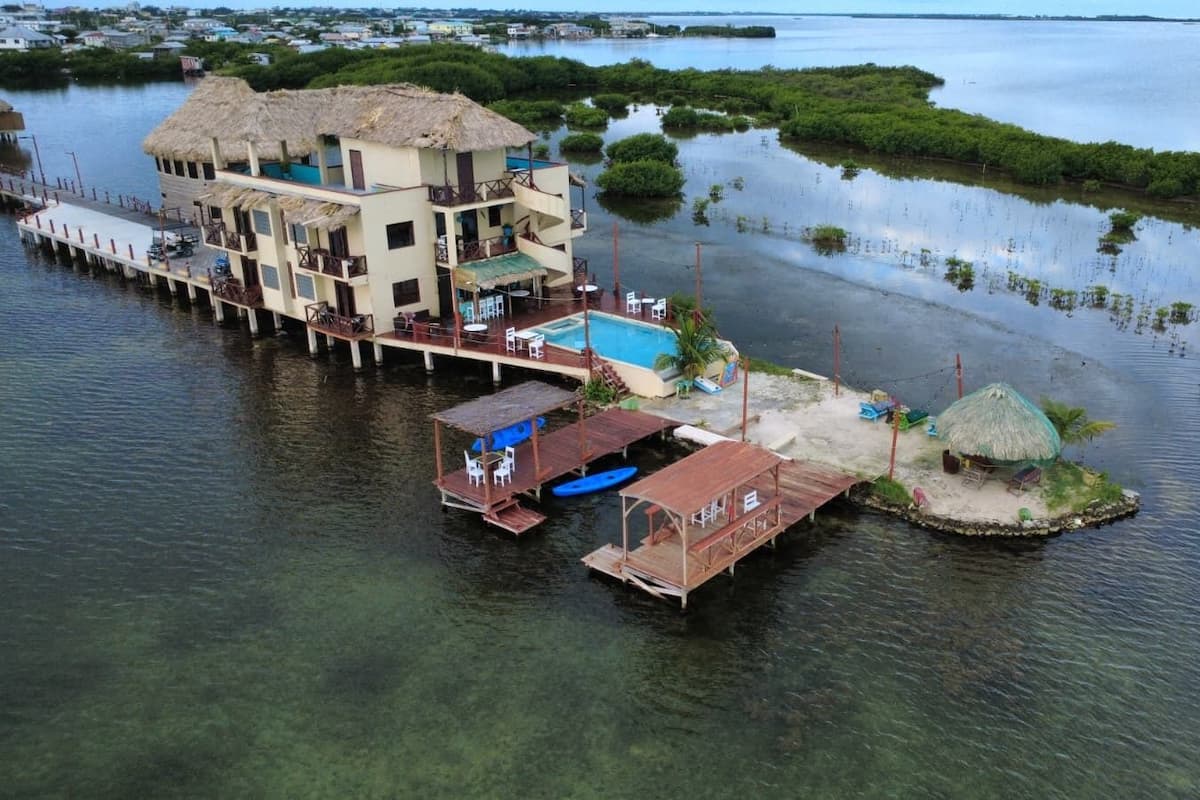A waterfront property with a large building, a dock, and a small island with a hut.