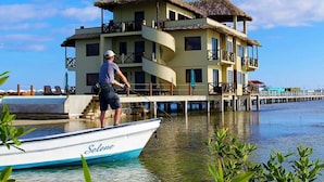 A multi-story building with a thatched roof, a dock, and a boat named "Selene" on the water. - Lina Point Belize Overwater Resort (San Pedro)