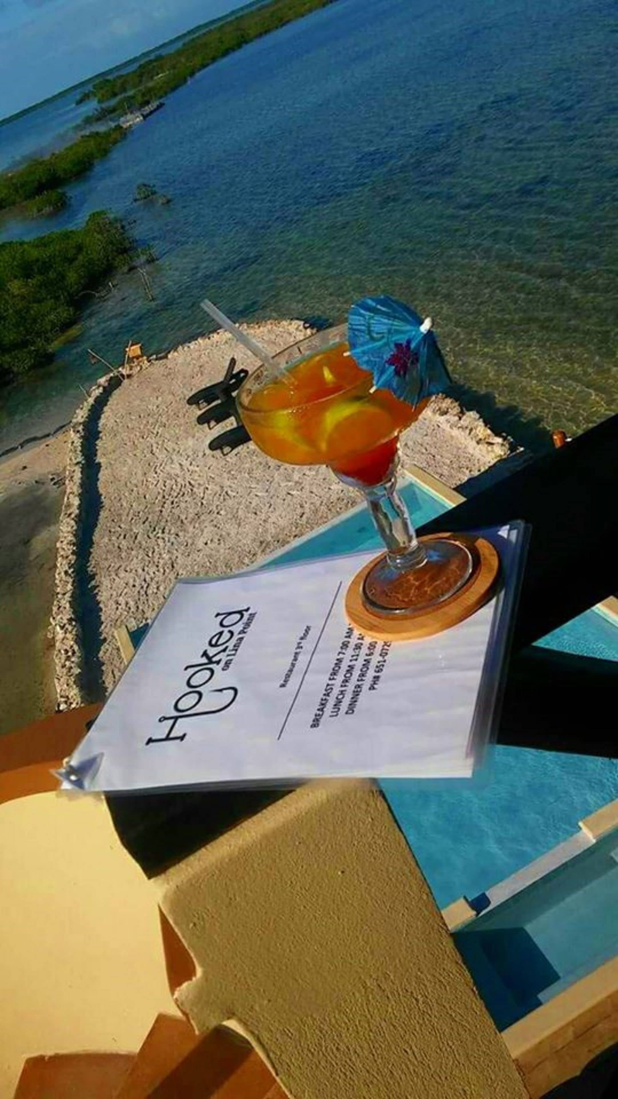 Um menu com uma bebida tropical e vista para uma praia e o mar.