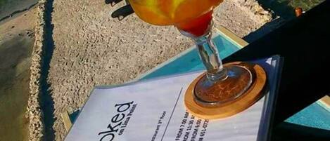 A menu with a tropical drink and a view of a beach and water.