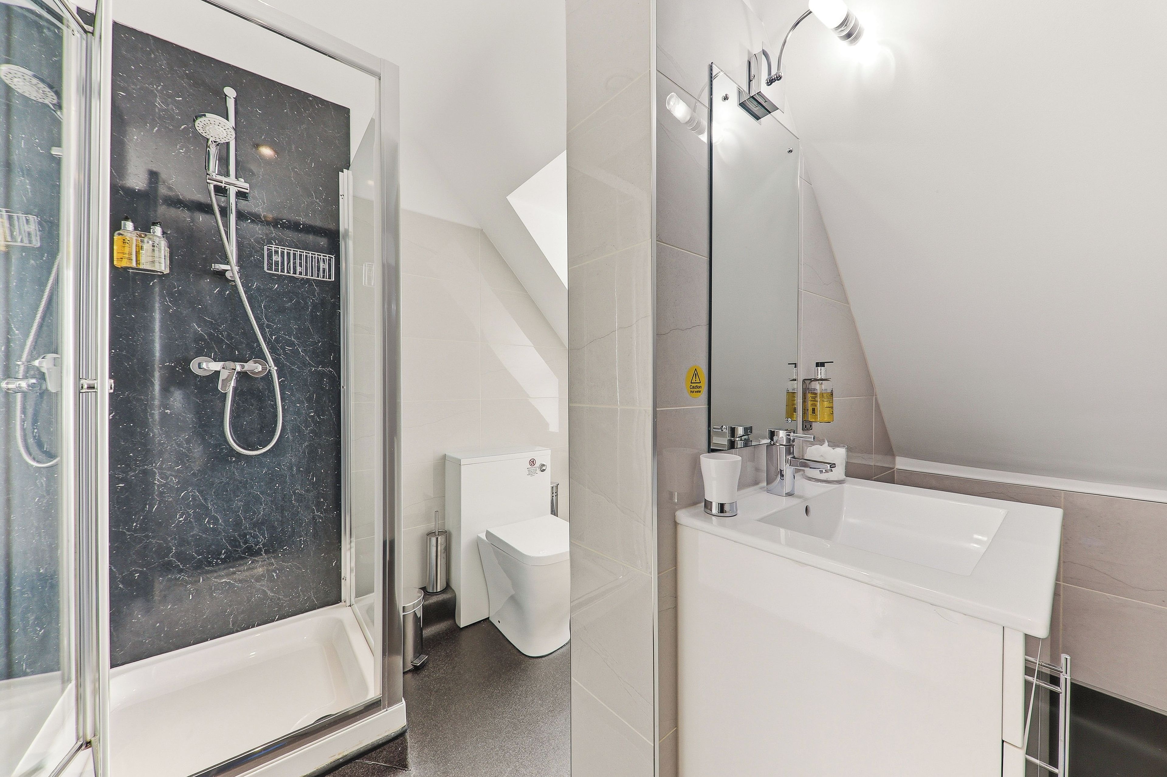 A modern bathroom with a glass-enclosed shower, a white sink, and a mirror.