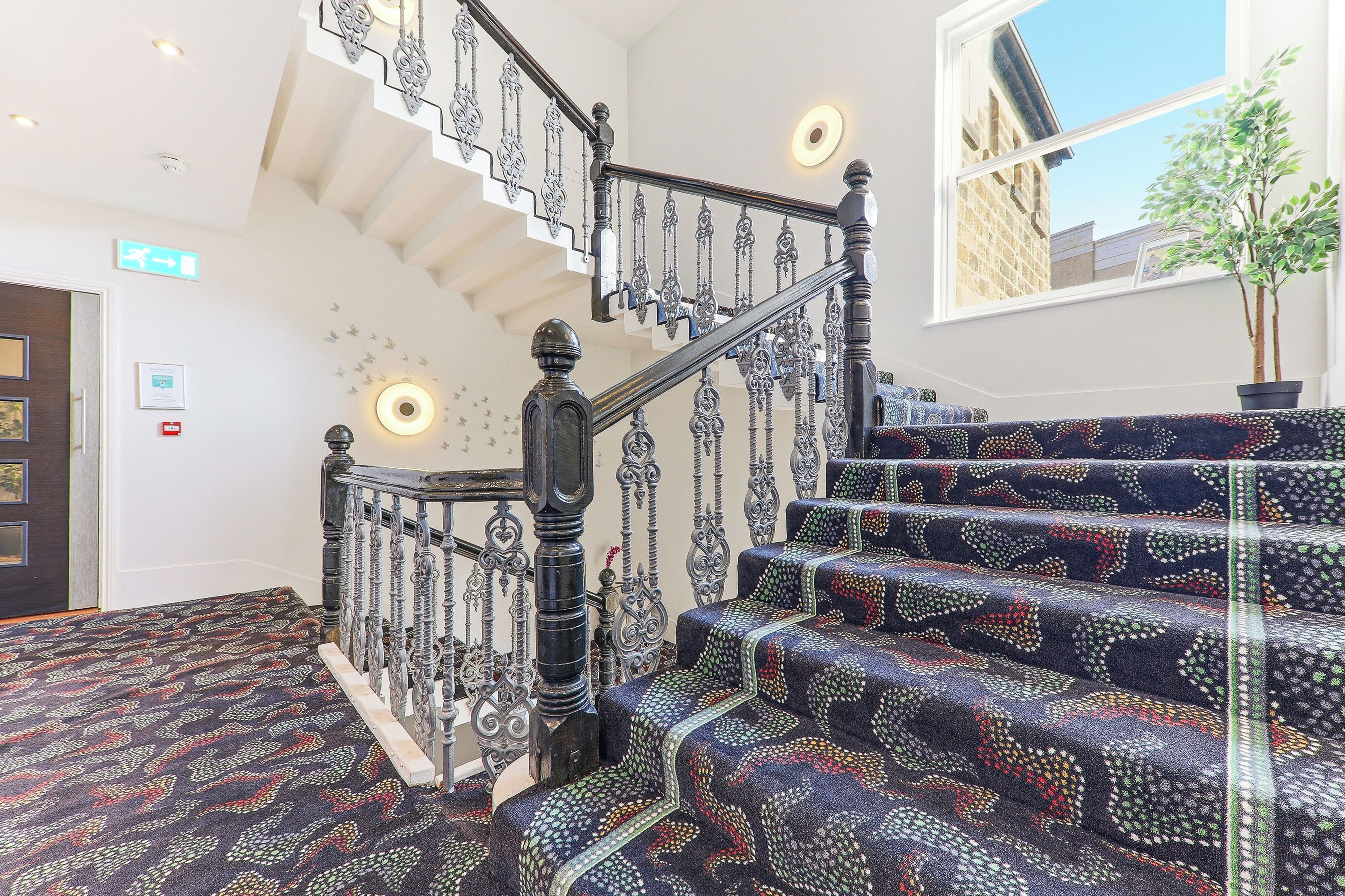 A staircase with ornate metal railings and patterned carpet.