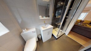 Un baño moderno con inodoro, lavabo y zona de ducha.