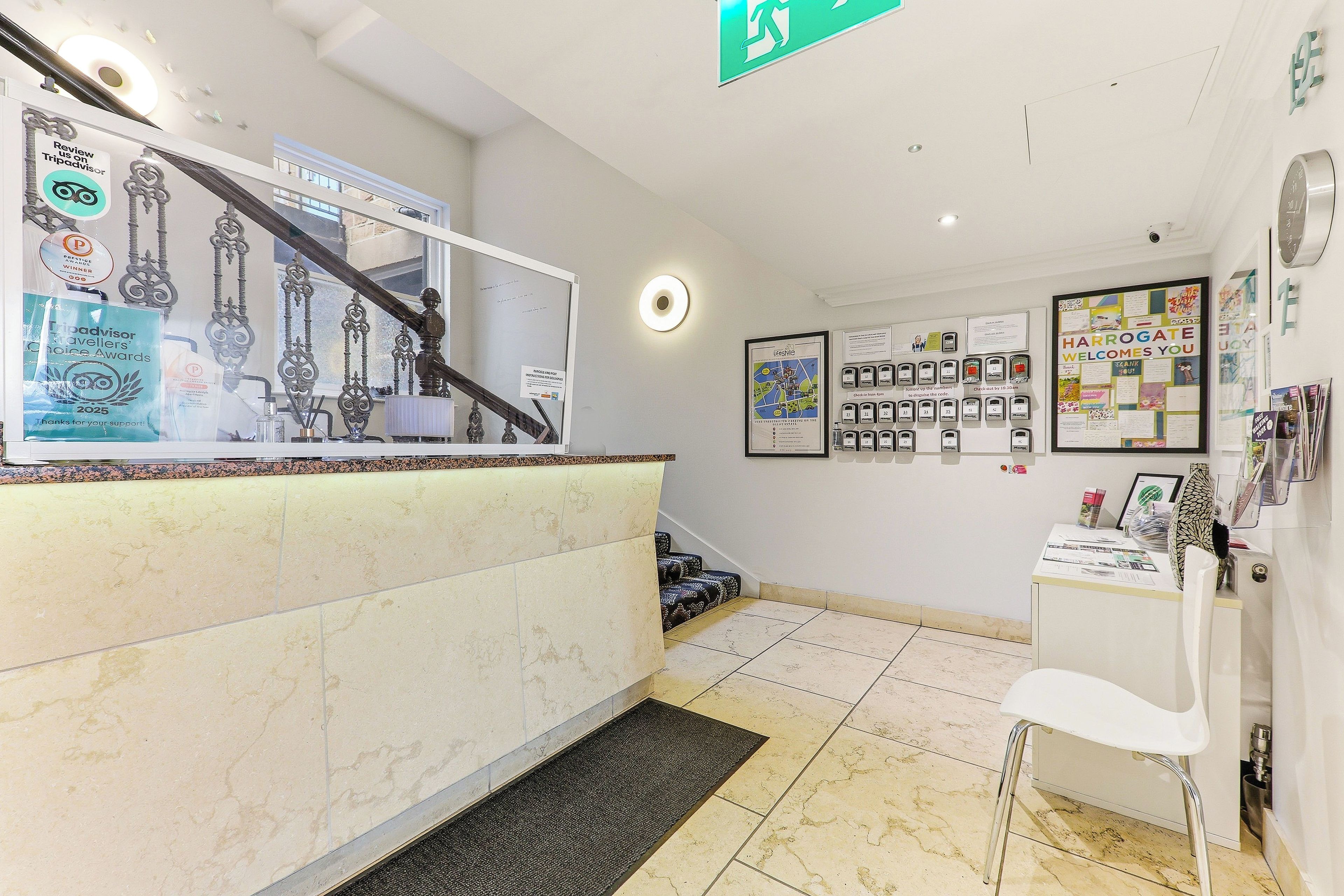 A reception area with a counter, a staircase, and a wall with various informational posters.