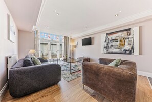 A modern living room with two sofas, a flat-screen TV, and a large abstract painting. - Harrogate Lifestyle Luxury Serviced ApartHotel (Harrogate)