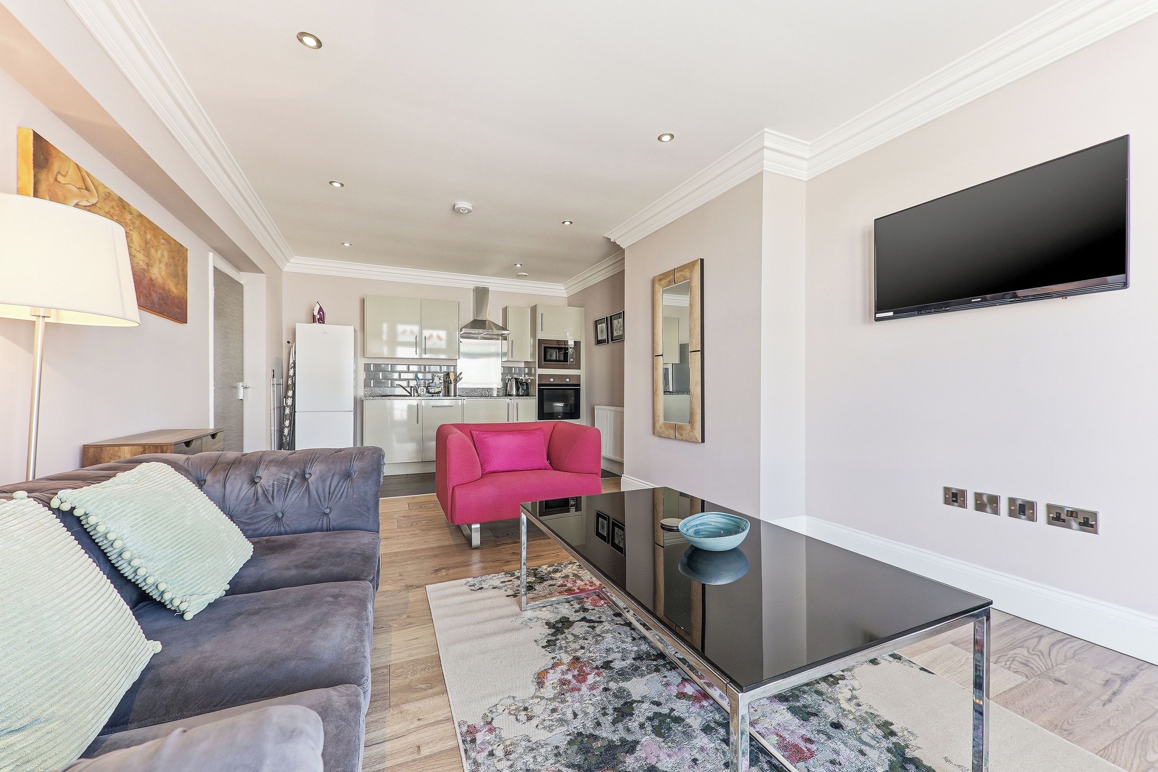 Un salon moderne avec un canapé, une table basse et un téléviseur à écran plat fixé au mur.