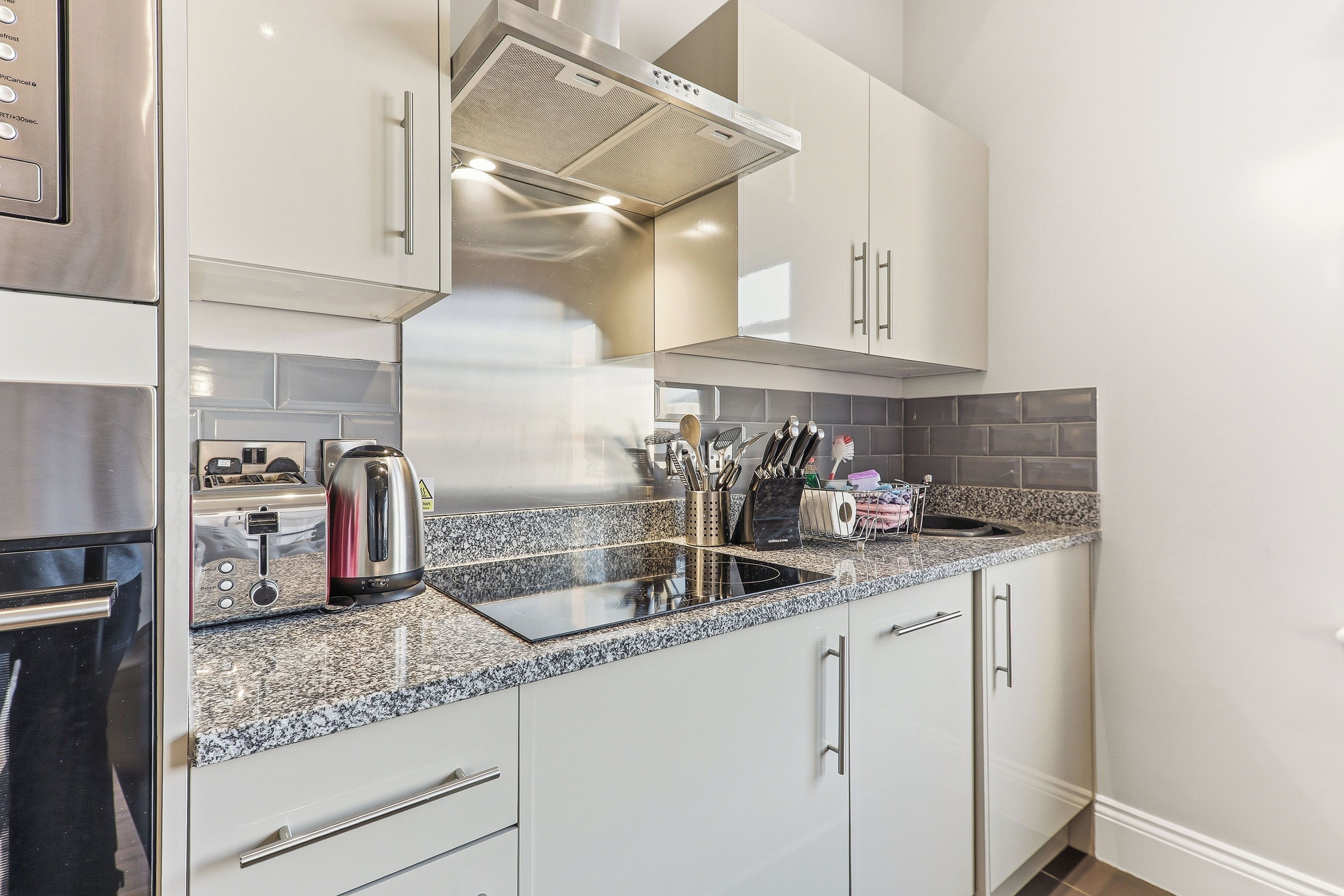 Eine moderne Küche mit Edelstahlgeräten, einer Granitarbeitsplatte und einem eingebauten Backofen.