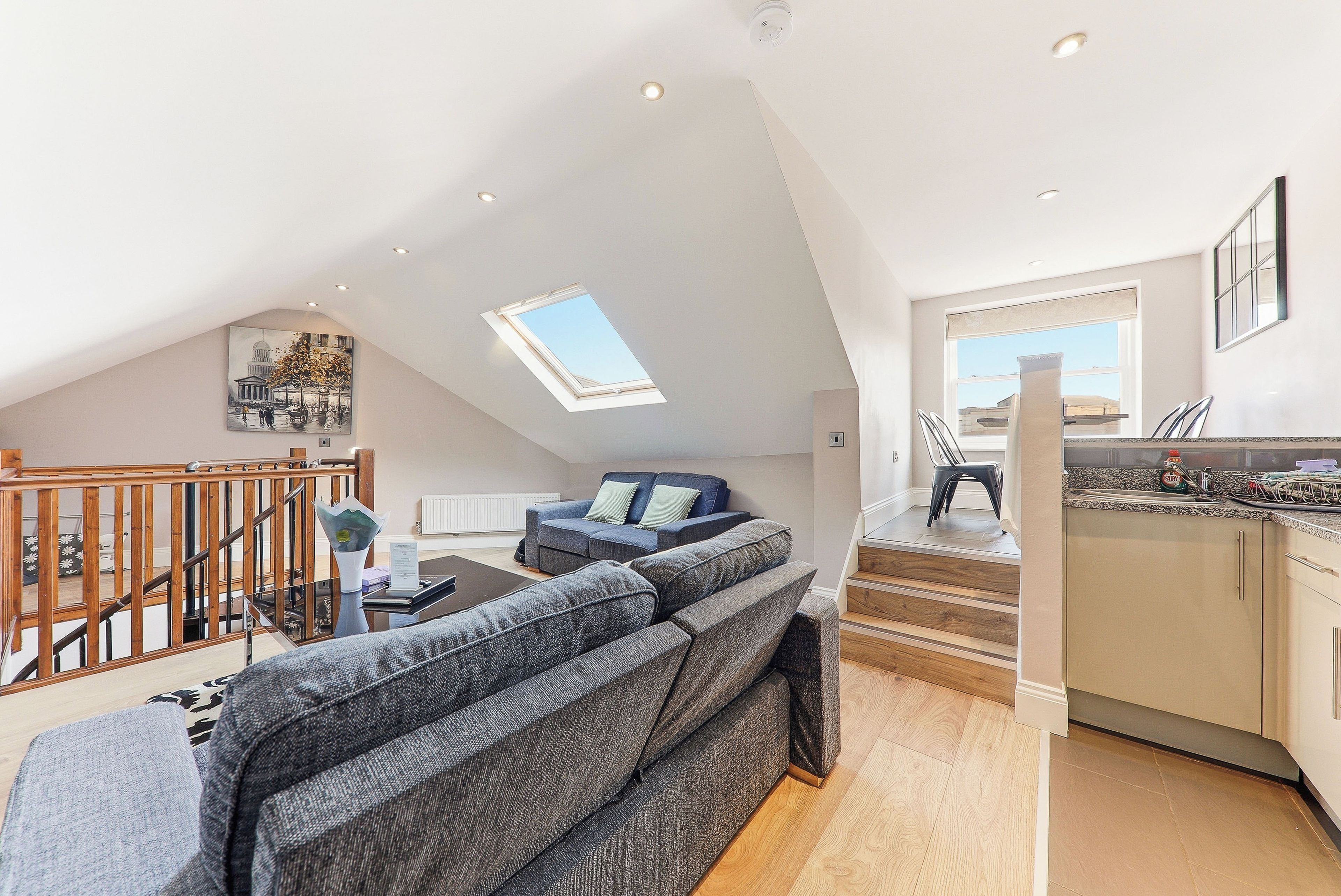 Ein geräumiges Loft mit hoher Decke, einem Oberlicht, einer Treppe, einer Wohnbereich mit einer Couch und einer Küchenzeile.