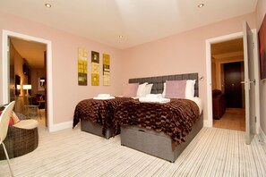 Un dormitorio con cama, mesitas de noche, una silla y una obra de arte en la pared.