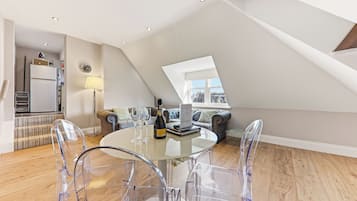 En moderne loftlejlighed med spiseplads, sofa og byudsigt.