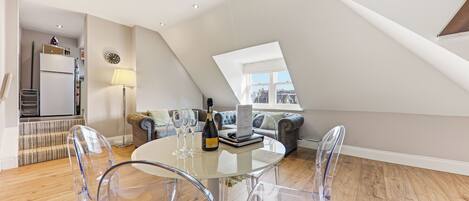 A modern loft apartment with a dining area, a sofa, and a view of the city.