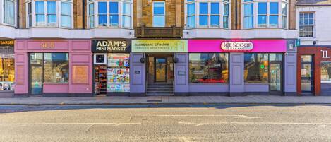 A row of shops including a barbershop, a mini market, a gelato store, and serviced apartments.