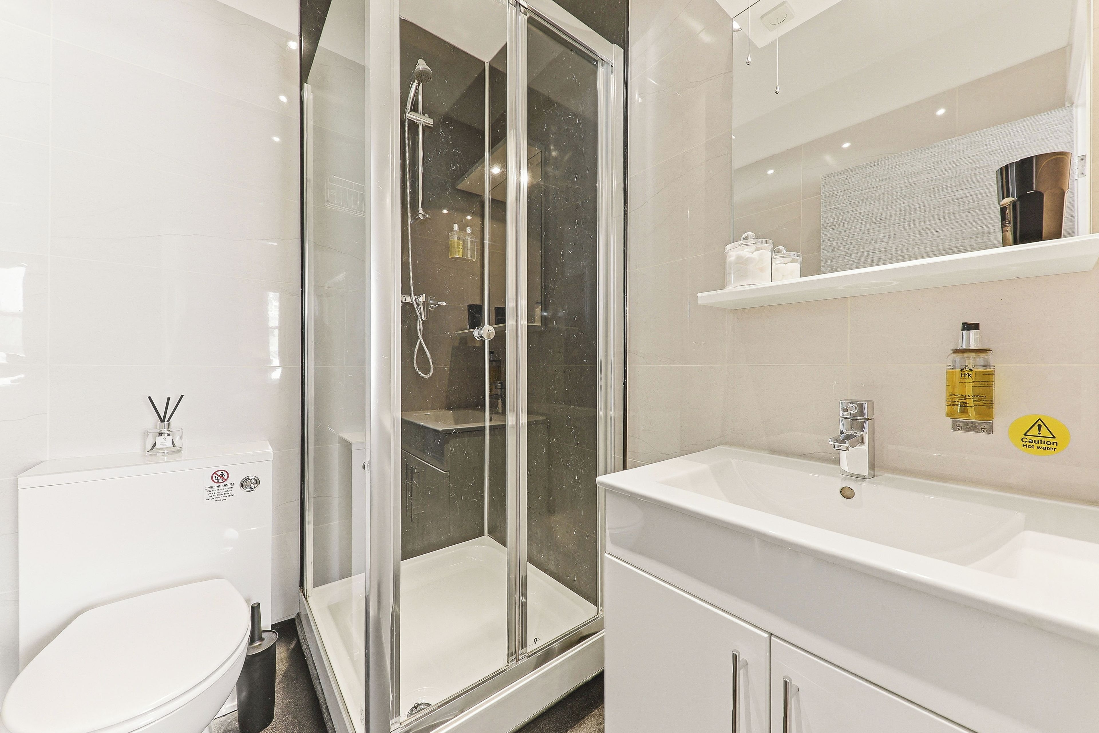 A modern bathroom with a glass-enclosed shower, a white sink, and a mirror above the sink.