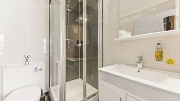 A modern bathroom with a glass-enclosed shower, a white sink, and a mirror above the sink.