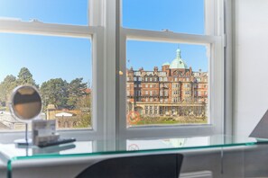 A view through a window of a building with a dome and multiple stories, a no parking sign, and a clear sky.