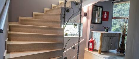 A spiral staircase with a small window at the top, a fire extinguisher, and a plant on the landing.