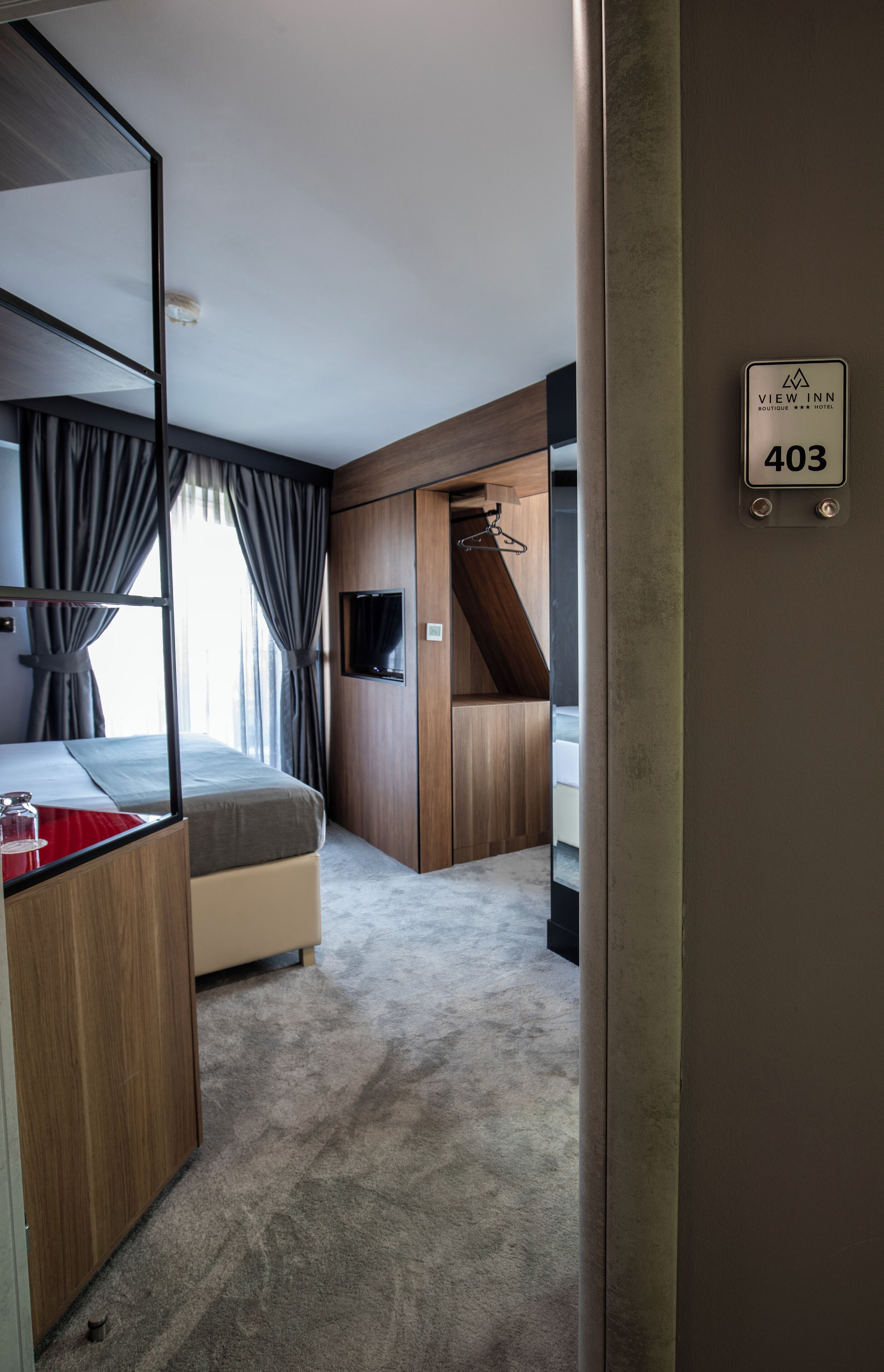 Habitación de hotel con cama, televisión, armario y zona de ducha.