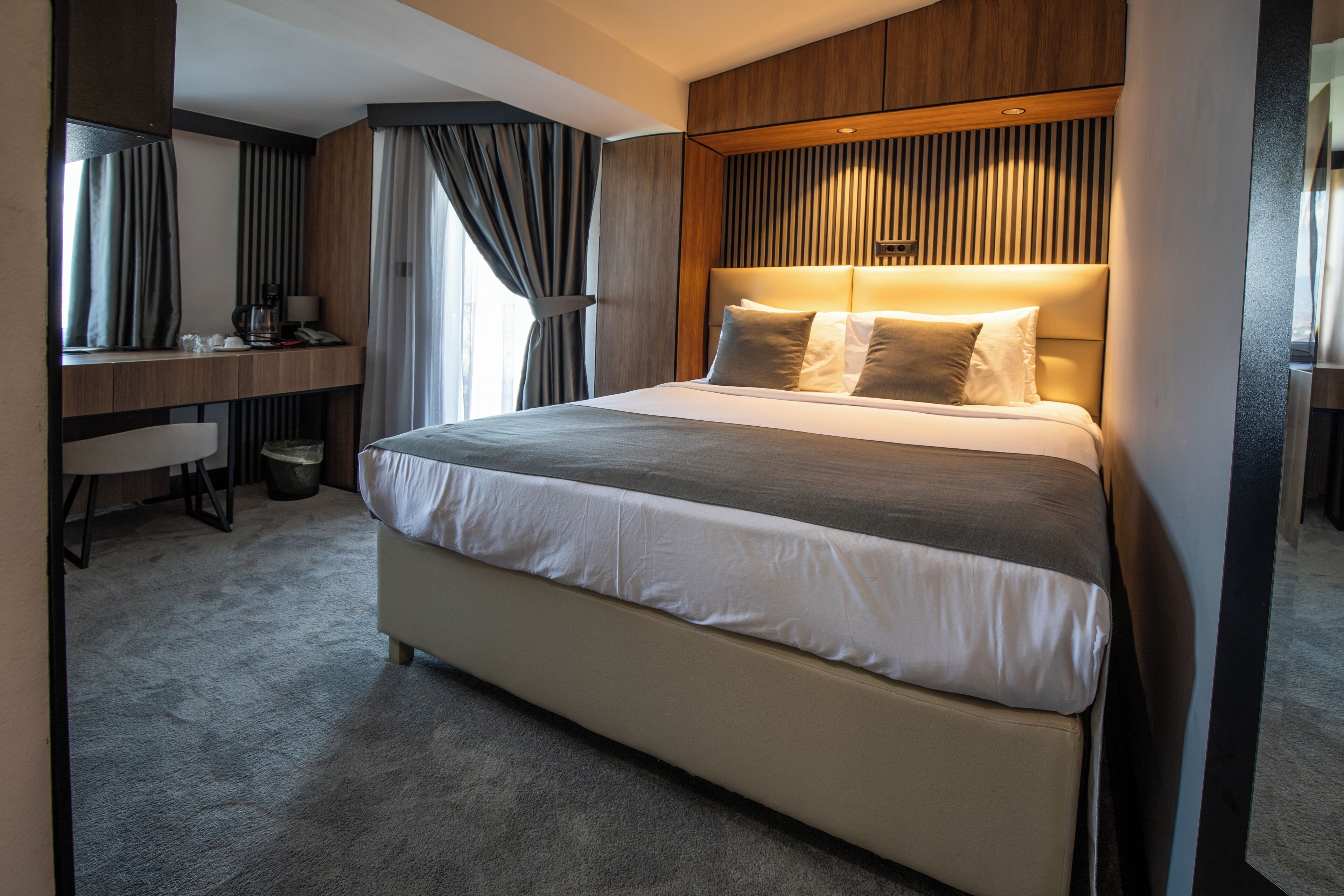 Een moderne hotelkamer met een groot bed, een bureau en een spiegel.