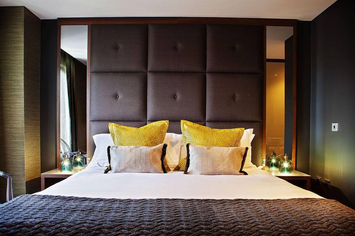 Een hotelkamer met een groot bed, een gestoffeerd hoofdeinde en decoratieve kussens.