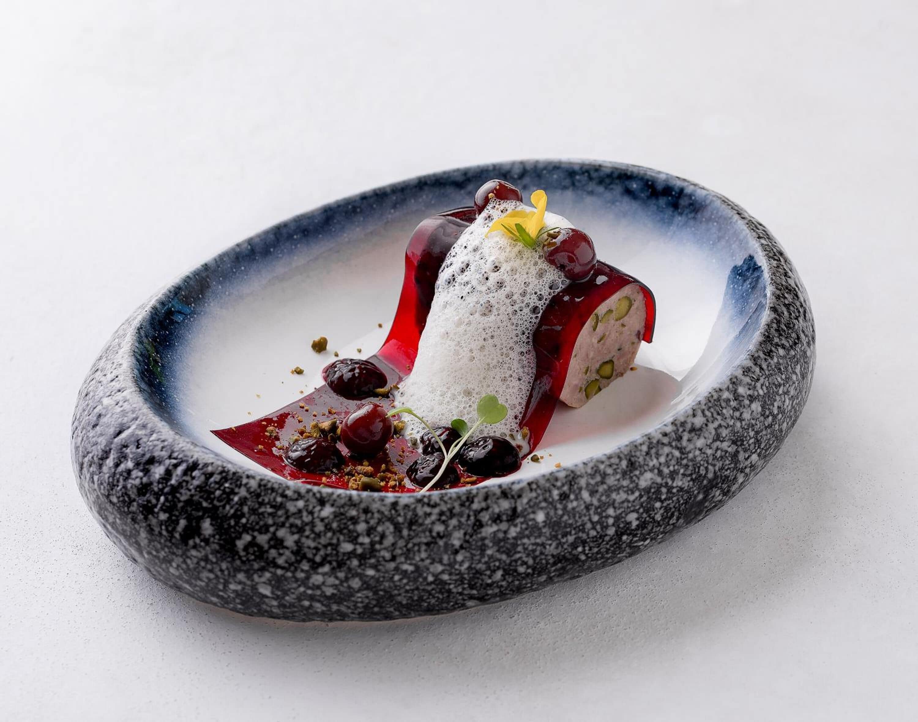 A dessert on a speckled stone plate with a white background.