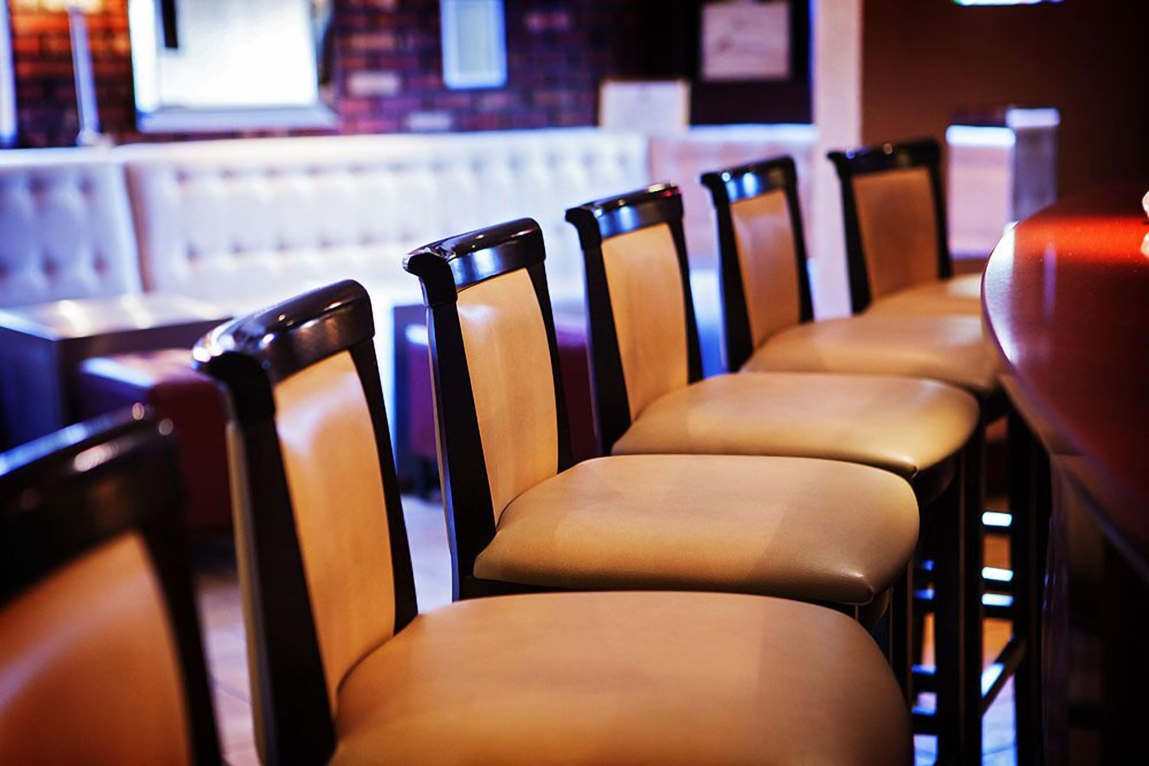 Een rij beige stoelen met zwarte poten, gerangschikt op een rij in een restaurant.