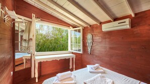 A wooden room with a bed, a window, a bench, and a wall-mounted air conditioner. - Can Mocamp (Kas)