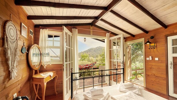 A wooden cabin room with a bed, a desk, and a view of the outdoors. - Can Mocamp (Kas)