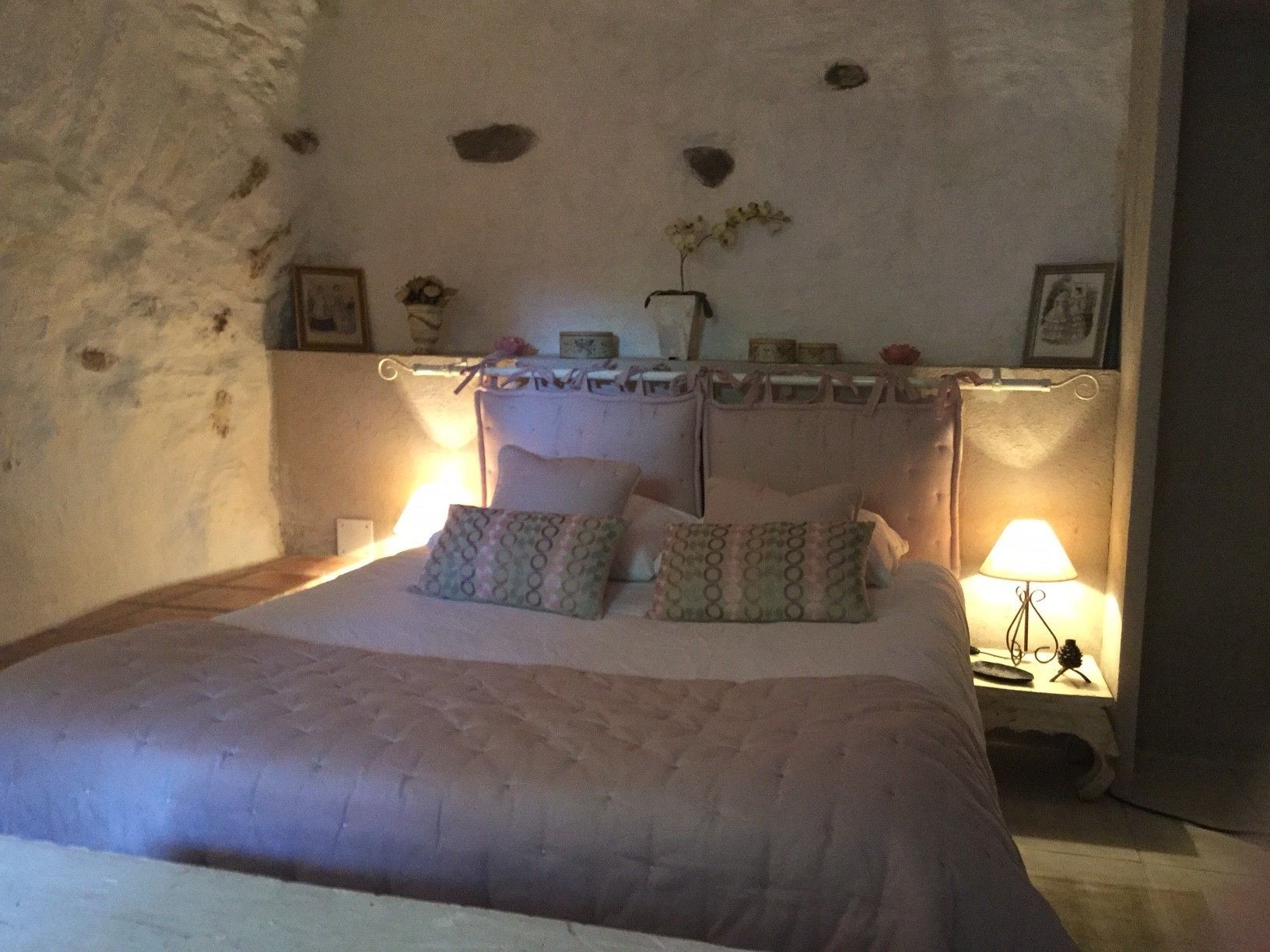 Een slaapkamer met een bed, twee bedlampen, een nachtkastje en een muur met een stenen patroon.