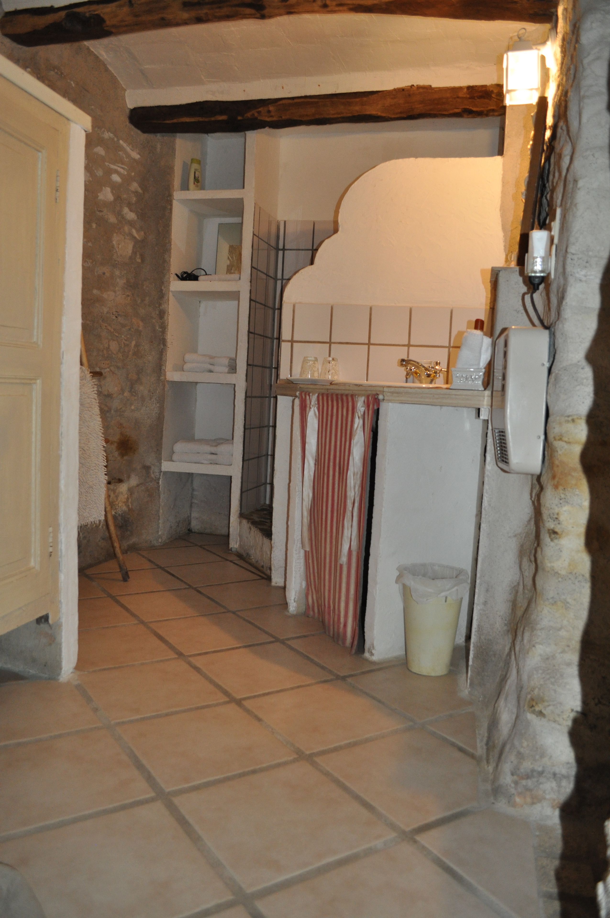 Une petite salle de bain avec un sol carrelé, un lavabo blanc et un porte-serviettes.
