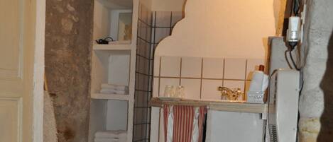 Une petite salle de bain avec un sol carrelé, un lavabo blanc et un porte-serviettes.