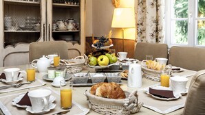 A breakfast setting with a table set for four, including plates, cups, and a variety of breakfast items like bread, fruits, and juice. - La Ribeyrette (Chamborigaud)