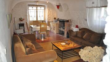 A cozy living room with a fireplace, a dining area, and a sofa.