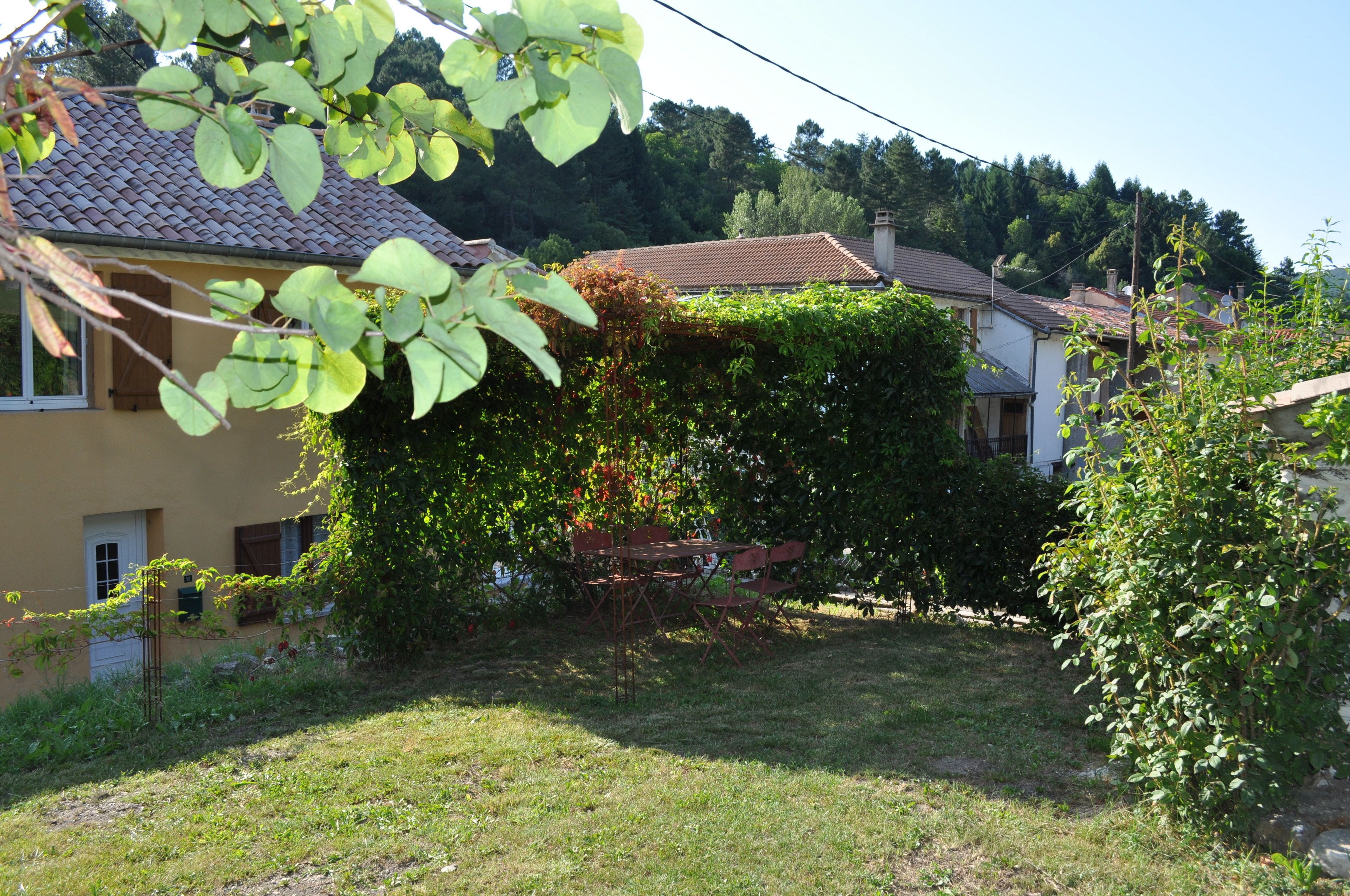 A house with a tiled roof, surrounded by greenery and a grassy yard.