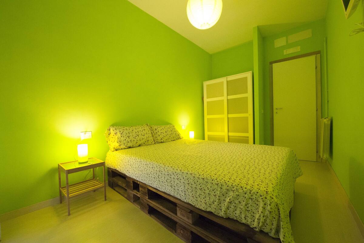 A room with a bed, a nightstand, and a door.