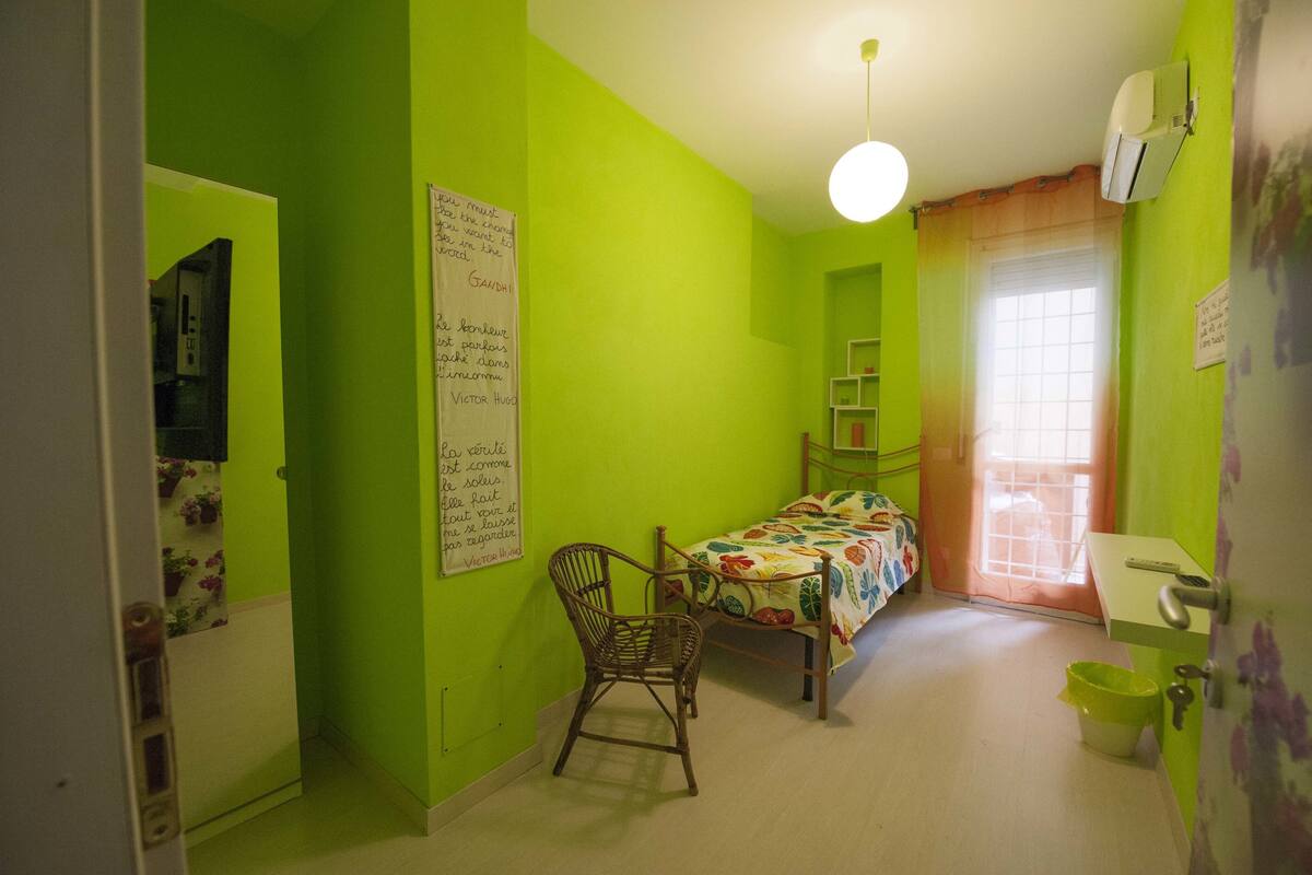 A room with a bed, a chair, a desk, and a window.