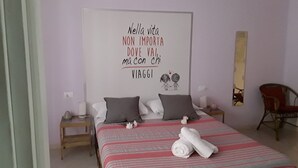 A bedroom with a bed, pillows, a bedside table, a chair, and a wall with a motivational quote. - B&B Da Ninetta (Rome)