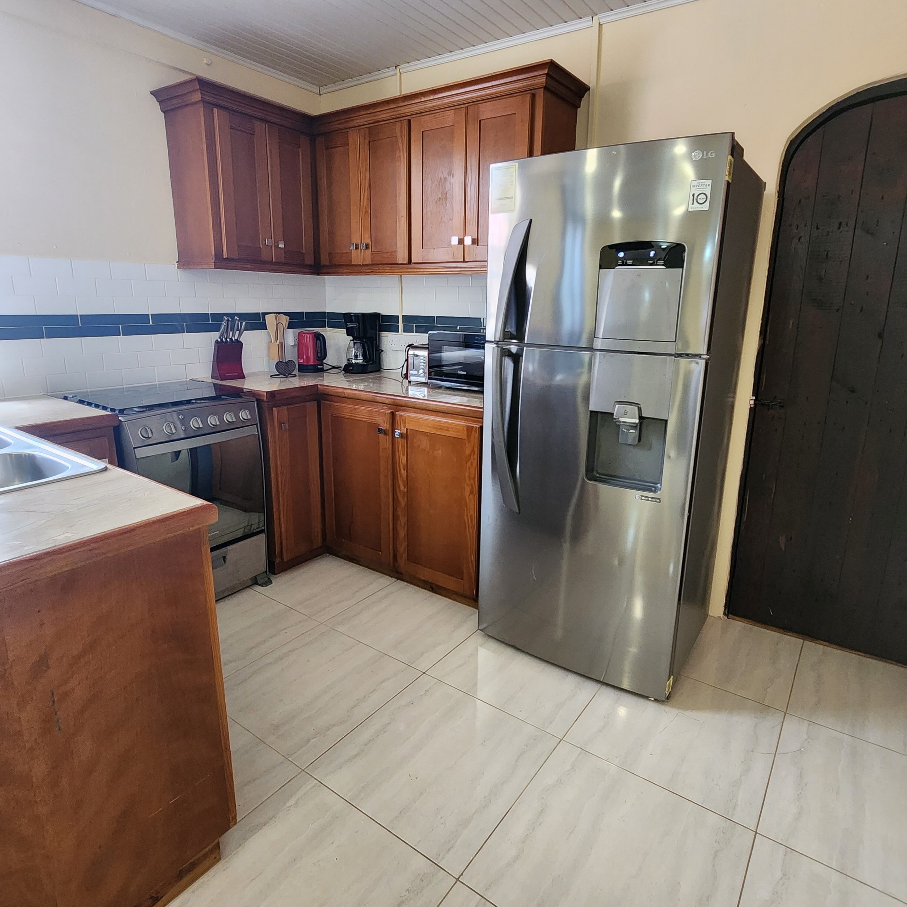 A kitchen with wooden cabinets, a stainless steel refrigerator, a stove, and a tiled backsplash.
