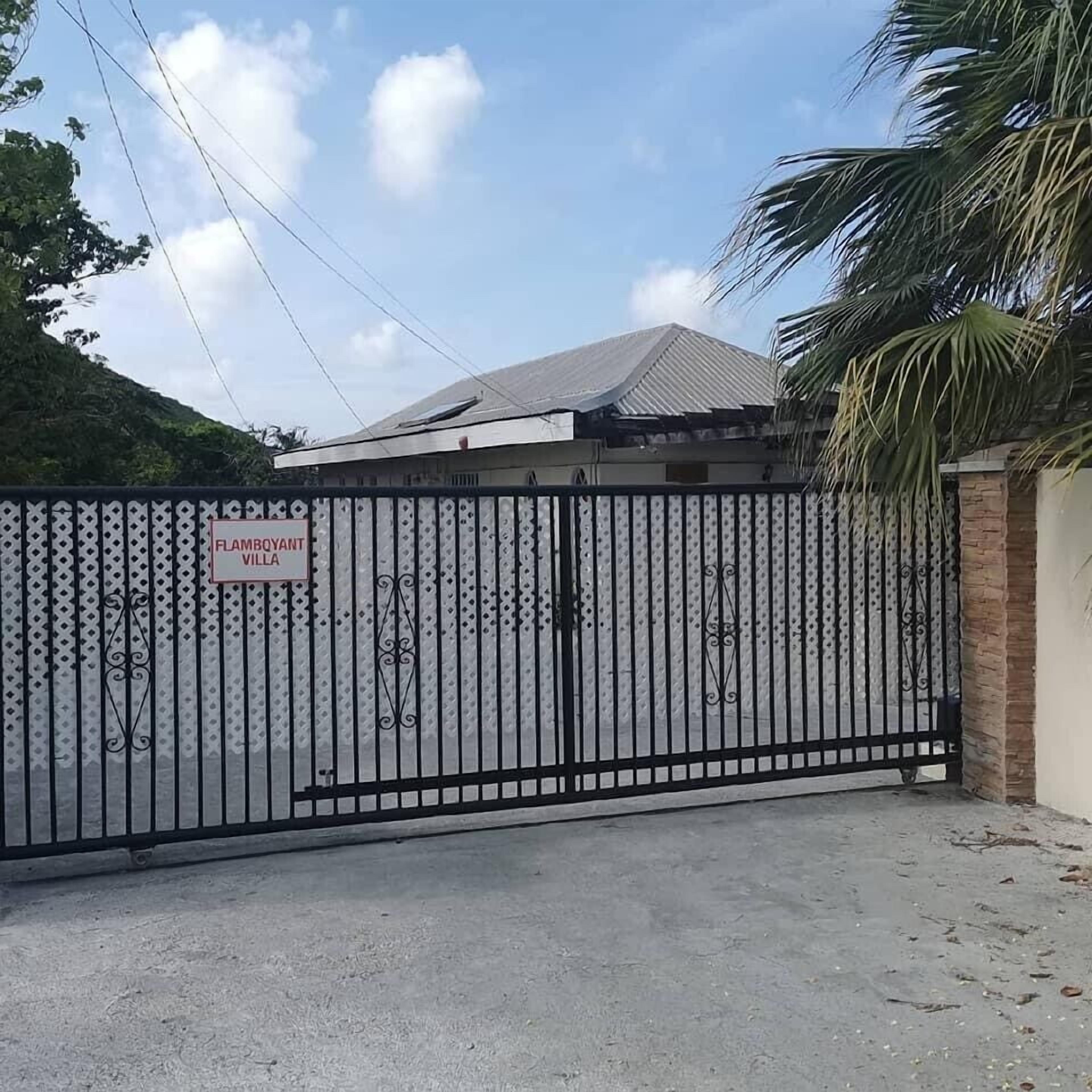 A gated entrance with a sign reading "FAMBOYANT VILLA".